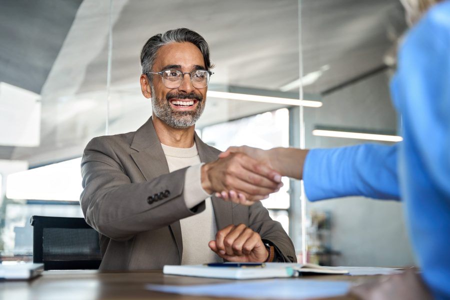 Mature smiling happy professional business man executive, male hr recruiter or bank manager hiring recruit at job interview onboarding corporate office meeting. Handshake with new client concept.